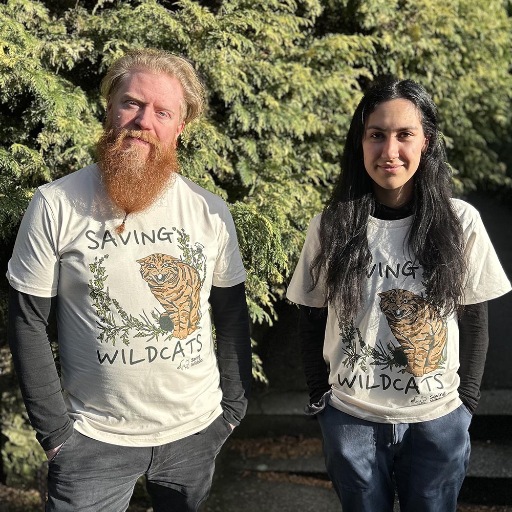 Support Saving Wildcats with this wild Saving Wildcats Men's T-shirt in Oat. The soft and sustainable organic cotton ensures you stay comfortable all day. The design features Ordie, one of the male wildcats in the Saving Wildcats conservation breeding for release centre that has fathered five wildcats that were released into the wild in 2023. His offspring include Arwen, who gave birth to two litters of wild born kittens in 2024 and Willie, a male wildcat that travelled all the way across the Cairngorms pla